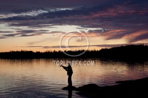 Fisherman silhouette on the beach at colorful sunset